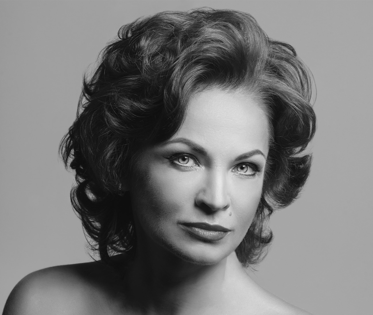 black and white photo of a woman posing for the camera, not fully smiling