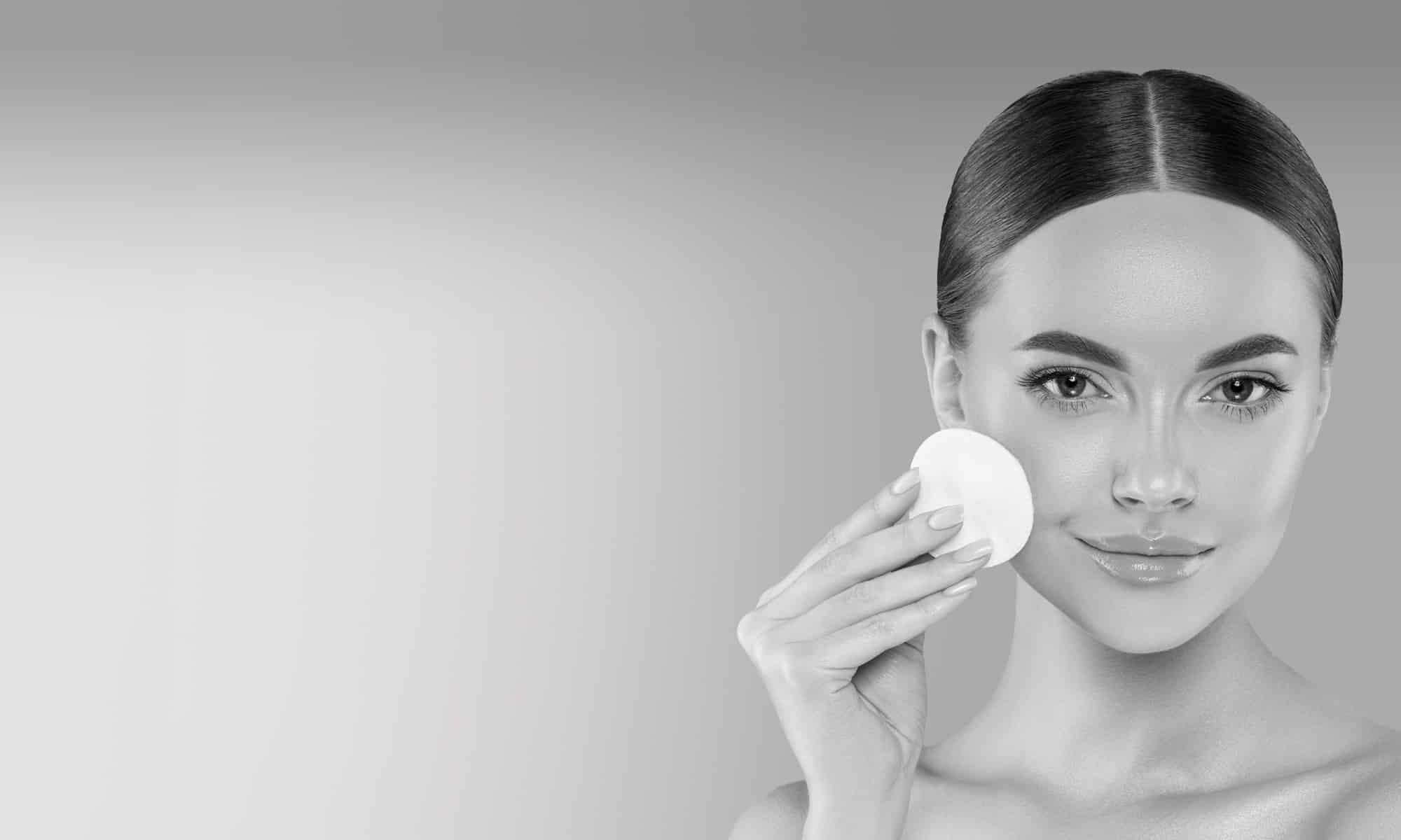 woman with a makeup pad poses for the camera, smiling