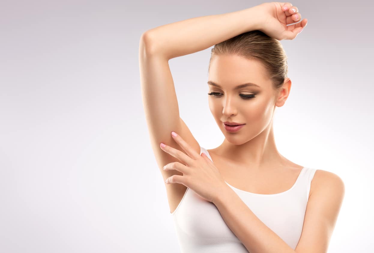 A Young Woman Dressed In A Sports Bra Is Touching The Clean, Soft Skin Of Her Armpit.